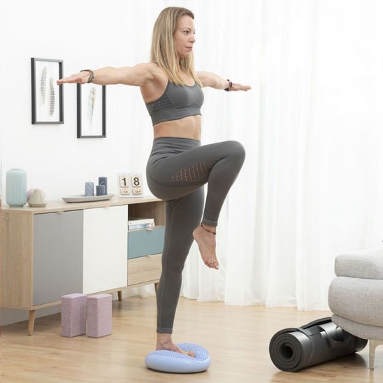 Femme debout sur un tapis pour pilates en équilibre sur une jambe pour travailler la stabilité et la posture