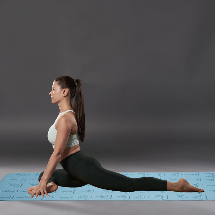 femme sur tapis yoga epais fait un exercice d'étirement de jambes