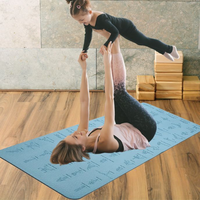 femme sur tapis yoga epais couchée sur son dos pieds dans l'air et elle tient sa fille posée sur ses pieds en équilibre